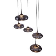 Mehrere moderne Pendelleuchten mit rauchgrauen Glas-Schirmen und warmem Licht, an schwarzen Kabeln hängend, in schräger Seitenansicht vor grauem Hintergrund