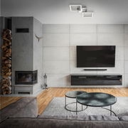 Moderne LED-Deckenleuchte in Chrom/Silber, von unten betrachtet in einem stilvollen Wohnzimmer mit grauer Wand und Kamin.