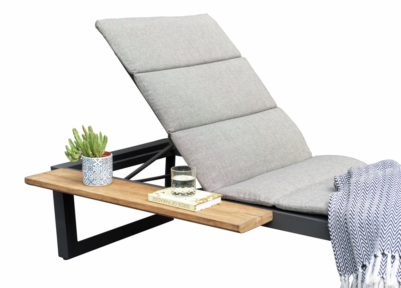 Seitliche Ansicht einer grauen Liege mit gepolstertem Kopfteil, einem Holztisch mit Kaktus, Glas Wasser und Buch.