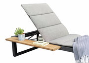 Seitliche Ansicht einer grauen Liege mit gepolstertem Kopfteil, einem Holztisch mit Kaktus, Glas Wasser und Buch.