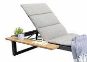 Seitliche Ansicht einer grauen Liege mit gepolstertem Kopfteil, einem Holztisch mit Kaktus, Glas Wasser und Buch.