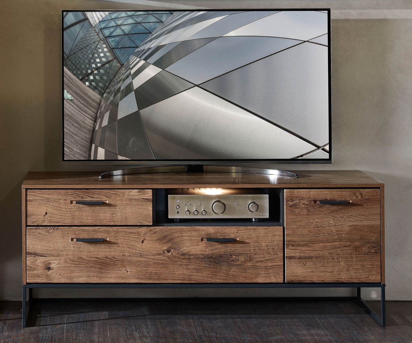 Zurbrüggen TV-Lowboard MANHATTAN TV-Lowboard MANHATTAN aus Holz mit Metallakzenten, frontal fotografiert, mit Schubladen und Stauraum, darauf ein moderner Flachbildfernseher.