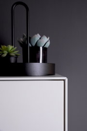 Close-up van een modern wit dressoir met decoratieve planten op het blad, gezien vanaf de zijkant.