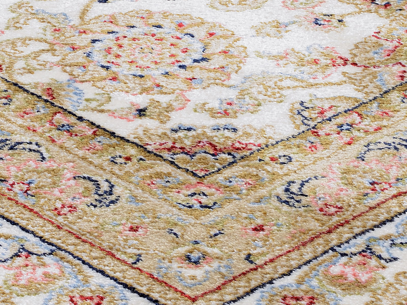 Nahaufnahme eines Orientteppichs mit floralen Mustern in Beige, Rot und Blau, schräg von oben fotografiert.