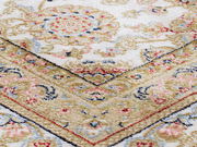 Nahaufnahme eines Orientteppichs mit floralen Mustern in Beige, Rot und Blau, schräg von oben fotografiert.