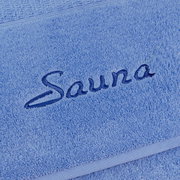 Nahaufnahme eines blauen Saunatuchs mit gesticktem Schriftzug 'Sauna'.