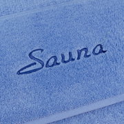 Nahaufnahme eines blauen Saunatuchs mit gesticktem Schriftzug 'Sauna'.