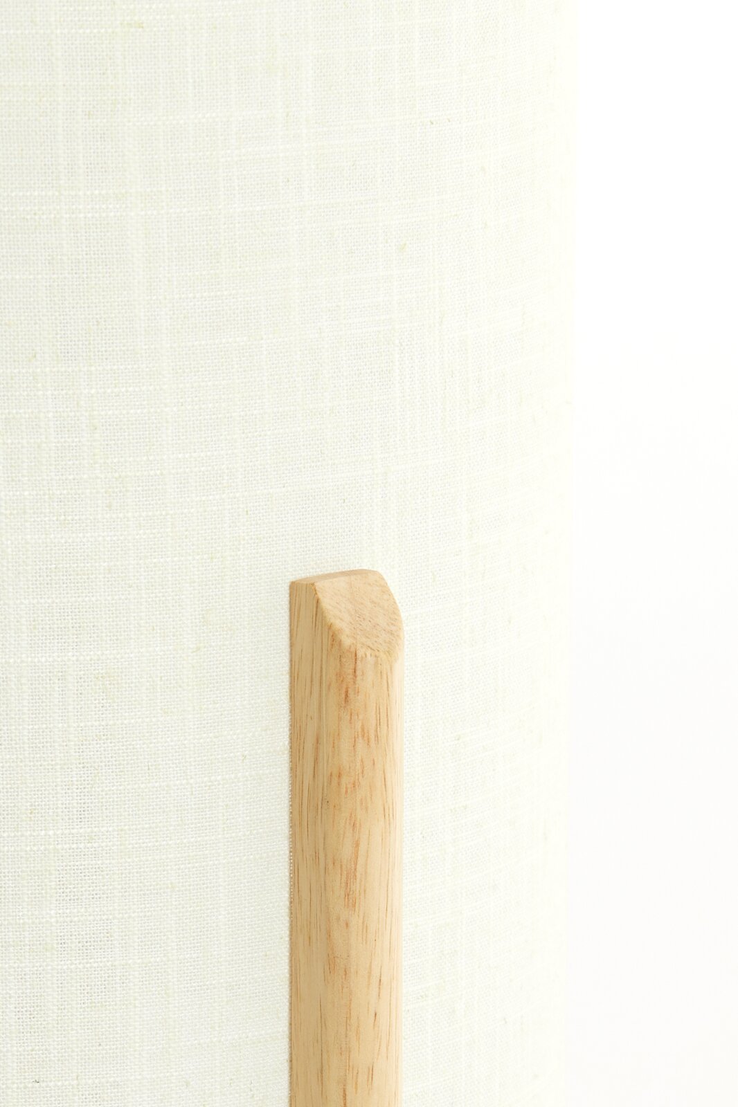 Nahaufnahme einer Tischleuchte mit hellem Stoffschirm und Holzdetail.