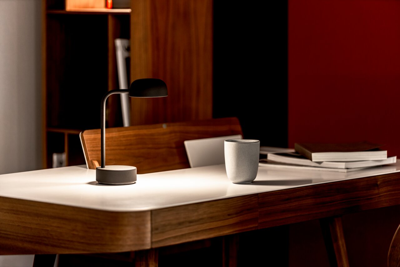 Moderne Tischlampe in Anthrazit auf einem eleganten Holztisch, seitliche Perspektive