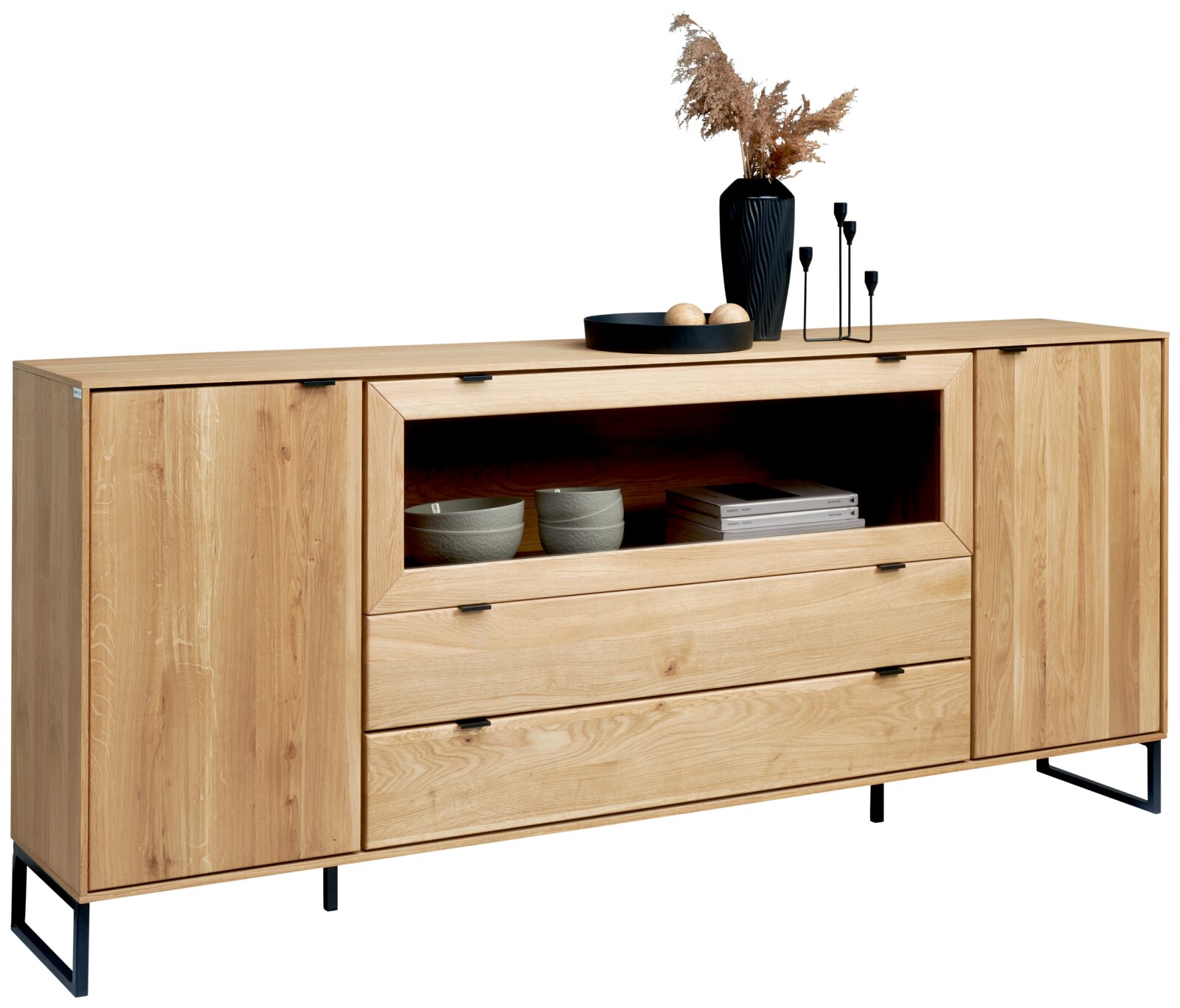 Licht eikenhouten dressoir met twee kastdeuren, open vak en drie lades op zwart metalen poten, gefotografeerd in vooraanzicht licht schuin van links, met decoratie bovenop