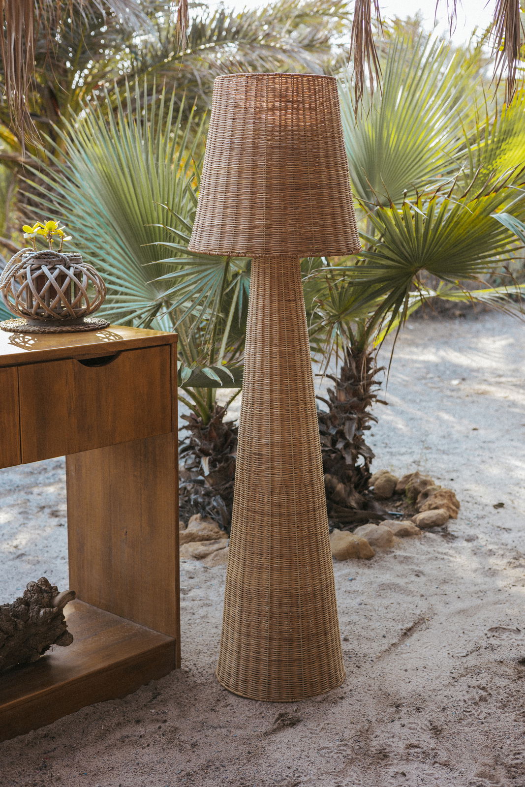 Akku-Outdoor-Stehleuchte aus Rattan in einem tropischen Garten, seitliche Perspektive