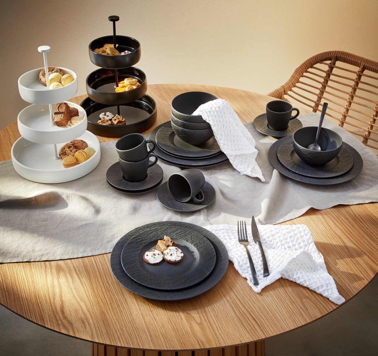 Elegantes 20-teiliges Geschirrset 'Manufacture Rock' in Schwarz auf einem gedeckten Tisch, mit Tassen, Tellern und Schalen in moderner Steinoptik, aus der Vogelperspektive fotografiert.
