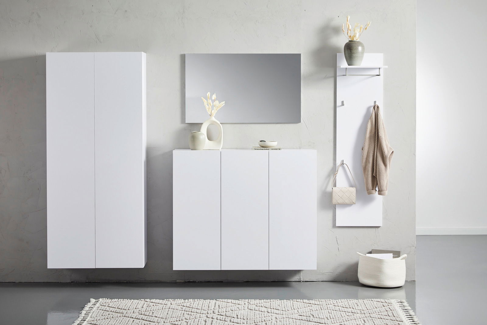 Moderne weiße Hängemöbel in einem minimalistischen Raum, frontal betrachtet. Links ein hoher Schrank, in der Mitte ein Sideboard mit Dekoration und rechts eine Garderobe mit Haken.