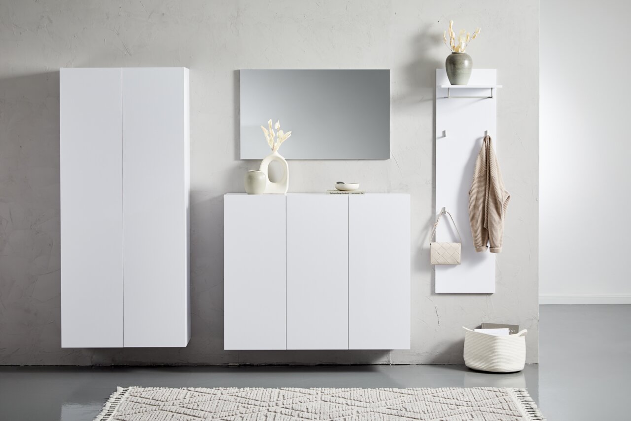 Moderne witte hangmeubels in een minimalistische ruimte, gezien vanaf de voorkant. Links een hoge kast, in het midden een dressoir met decoratie en rechts een kapstok met haken.