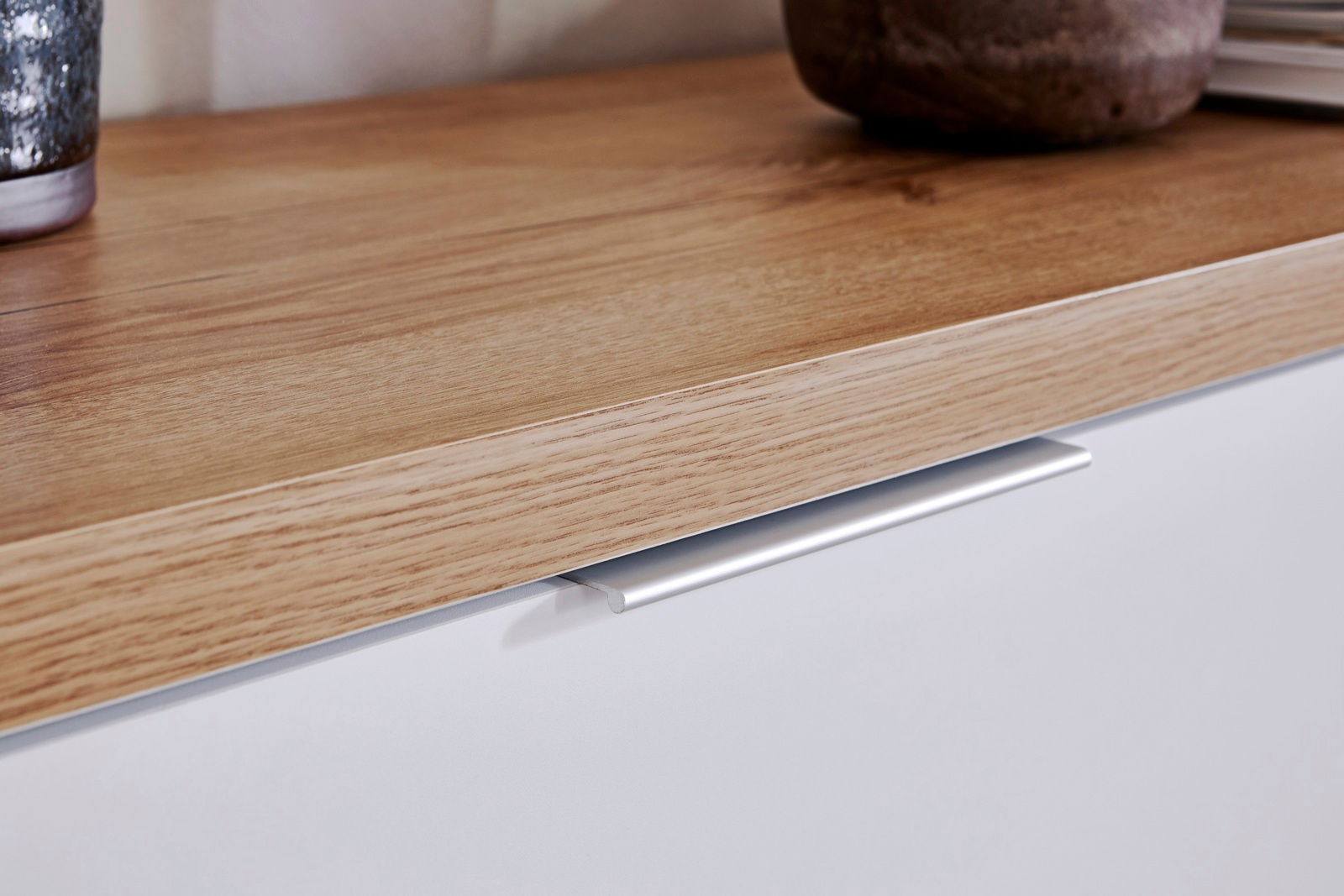 Nahaufnahme eines Sideboards mit Holzoberfläche und weißer Front, seitliche Perspektive