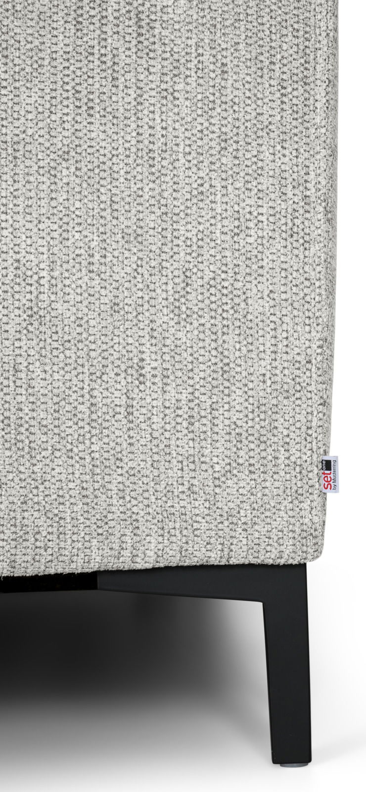 Nahaufnahme einer grauen, texturierten Stoffoberfläche eines Möbels mit schwarzem Metallfuß, seitliche Perspektive.