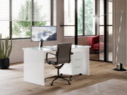 Moderner weißer Schreibtisch mit Glasplatte und Rollcontainer, seitliche Perspektive in einem stilvollen Büro mit großen Fenstern.