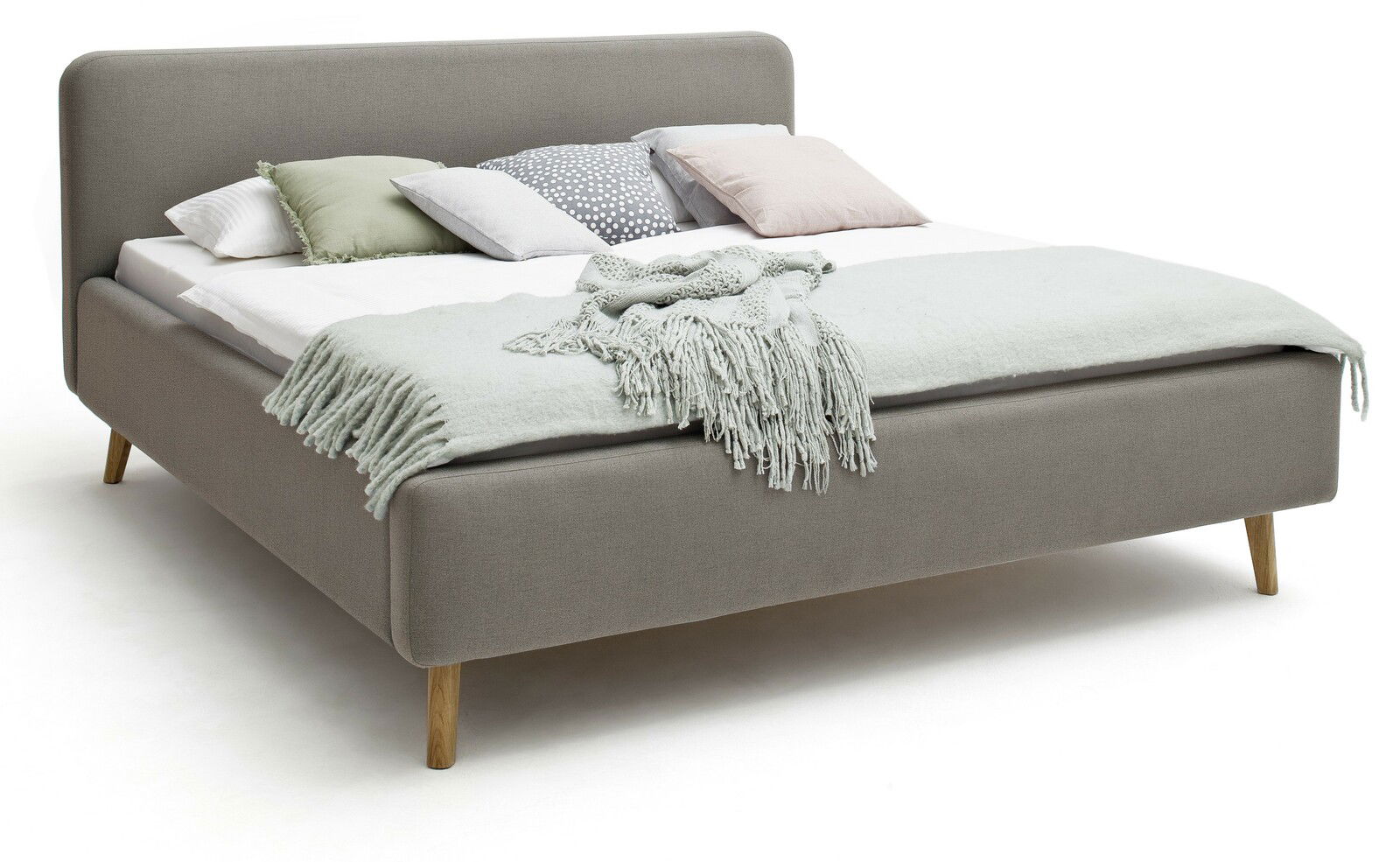 Graues Polsterbett mit Holzfüßen, dekoriert mit mehreren Kissen und einer Decke, seitliche Perspektive