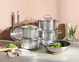 Topfset ELEGANCE 6-tlg. aus Edelstahl, bestehend aus mehreren Töpfen und Pfannen, auf einer Küchenarbeitsplatte arrangiert. Perspektive von vorne.