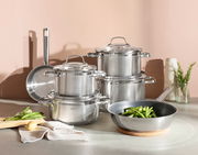 Topfset ELEGANCE 6-tlg. aus Edelstahl, bestehend aus mehreren Töpfen und Pfannen, auf einer Küchenarbeitsplatte arrangiert. Perspektive von vorne.