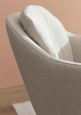 Nahaufnahme eines beigen Armlehnstuhls mit texturierter Oberfläche, seitliche Perspektive