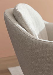 Nahaufnahme eines beigen Armlehnstuhls mit texturierter Oberfläche, seitliche Perspektive