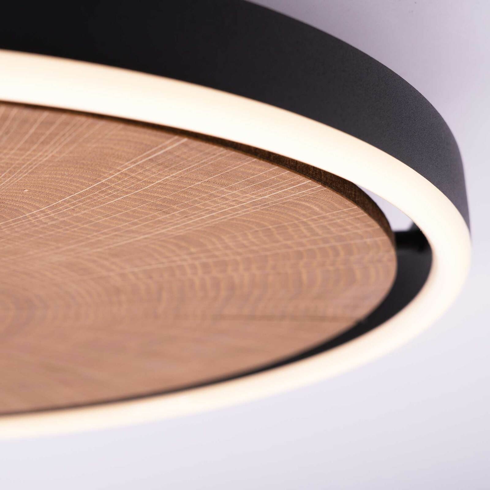 Nahaufnahme einer LED-Deckenleuchte mit Holzoptik und schwarzem Rand, seitliche Perspektive