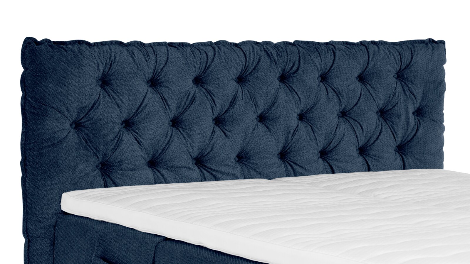 Gepolstertes, dunkelblaues Bettkopfteil mit Chesterfield-Knopfheftung und sichtbarer weißer Matratze, schräg von vorne (3/4-Perspektive) fotografiert.