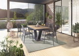 Moderner Essbereich im Freien mit stilvollen Sesseln und einem Tisch auf einer Terrasse mit Blick auf die Natur, aus seitlicher Perspektive.