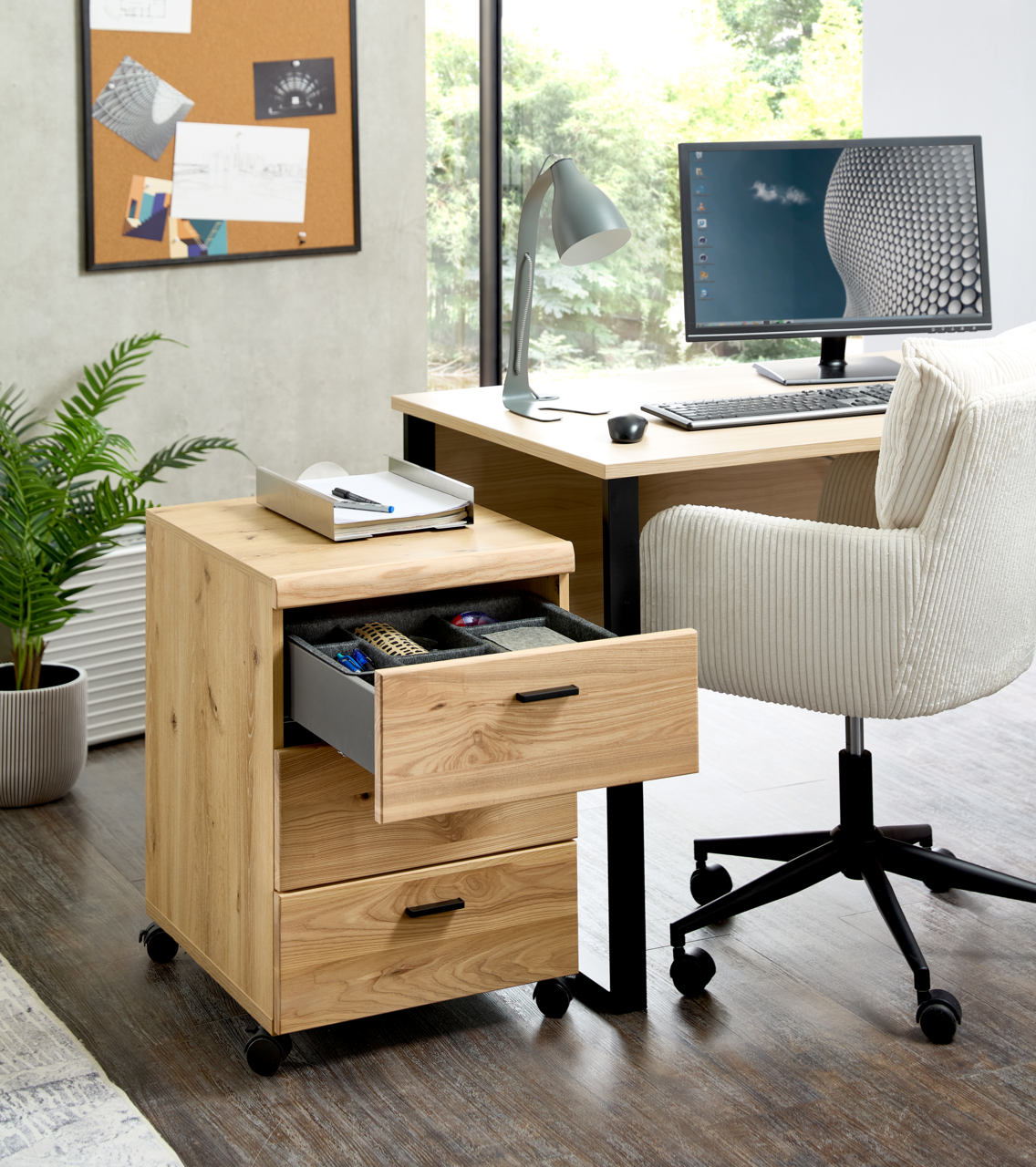 Rollcontainer aus Holz mit drei Schubladen, auf Rollen, in einem modernen Büro neben einem Schreibtisch, Perspektive von vorne links