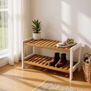 Zweistufige Schuhbank/Schuhregal aus Holz mit weißem Rahmen im hellen Flur, mit Pflanze und Schuhen dekoriert, fotografiert in leichter Seitenansicht von vorn.
