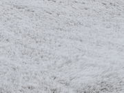 Nahaufnahme eines weichen, flauschigen Fellteppichs in grauer Farbe, von oben betrachtet.