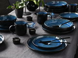 Elegantes 30-teiliges Kombiservice in Blau und Schwarz, auf einem gedeckten Tisch von oben fotografiert.