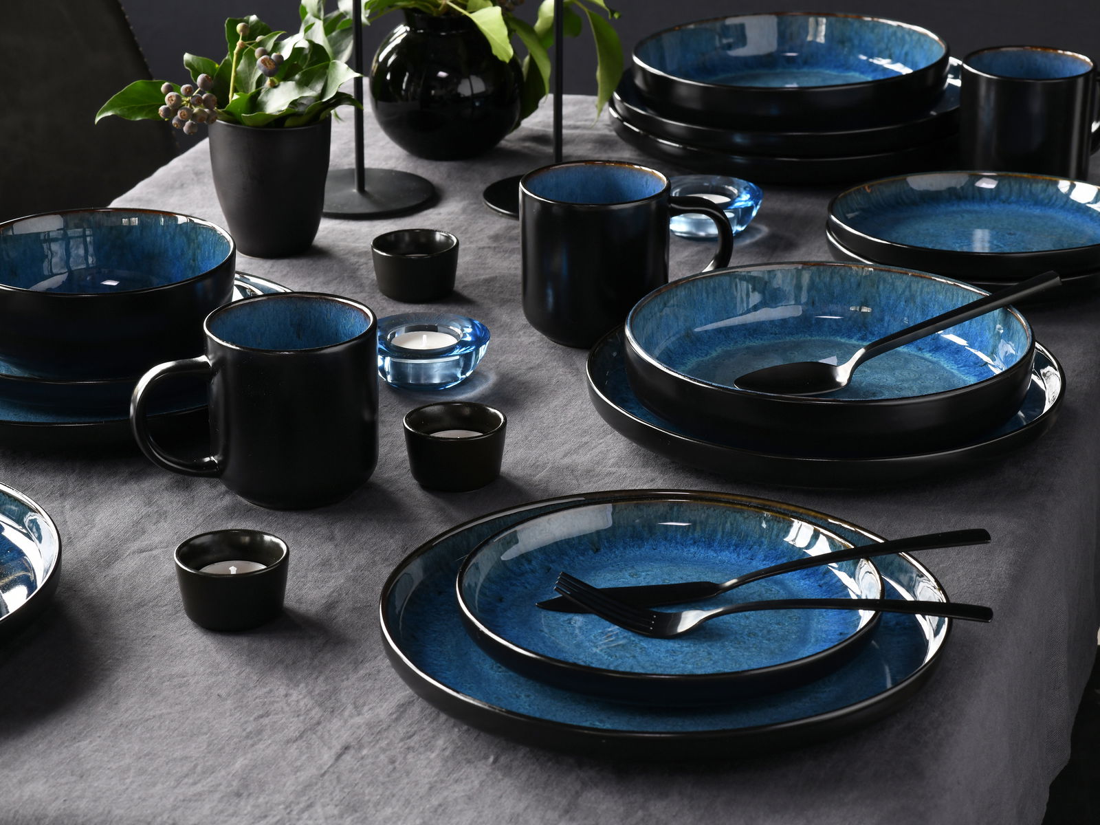 Elegantes 30-teiliges Kombiservice in Blau und Schwarz, auf einem gedeckten Tisch von oben fotografiert.
