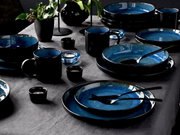Elegant 30-delig servies in blauw en zwart, van bovenaf gefotografeerd op een gedekte tafel.