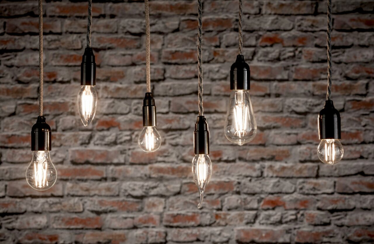 PAULMANN LED-Leuchtmittel URAIL Mehrere hängende LED-Leuchtmittel vor einer Ziegelwand, seitliche Perspektive.