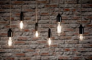 Mehrere hängende LED-Leuchtmittel vor einer Ziegelwand, seitliche Perspektive.