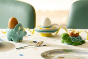Eierbecher in Form einer Schildkröte aus Keramik, auf einem Tisch mit einem halbierten Ei, seitliche Perspektive.