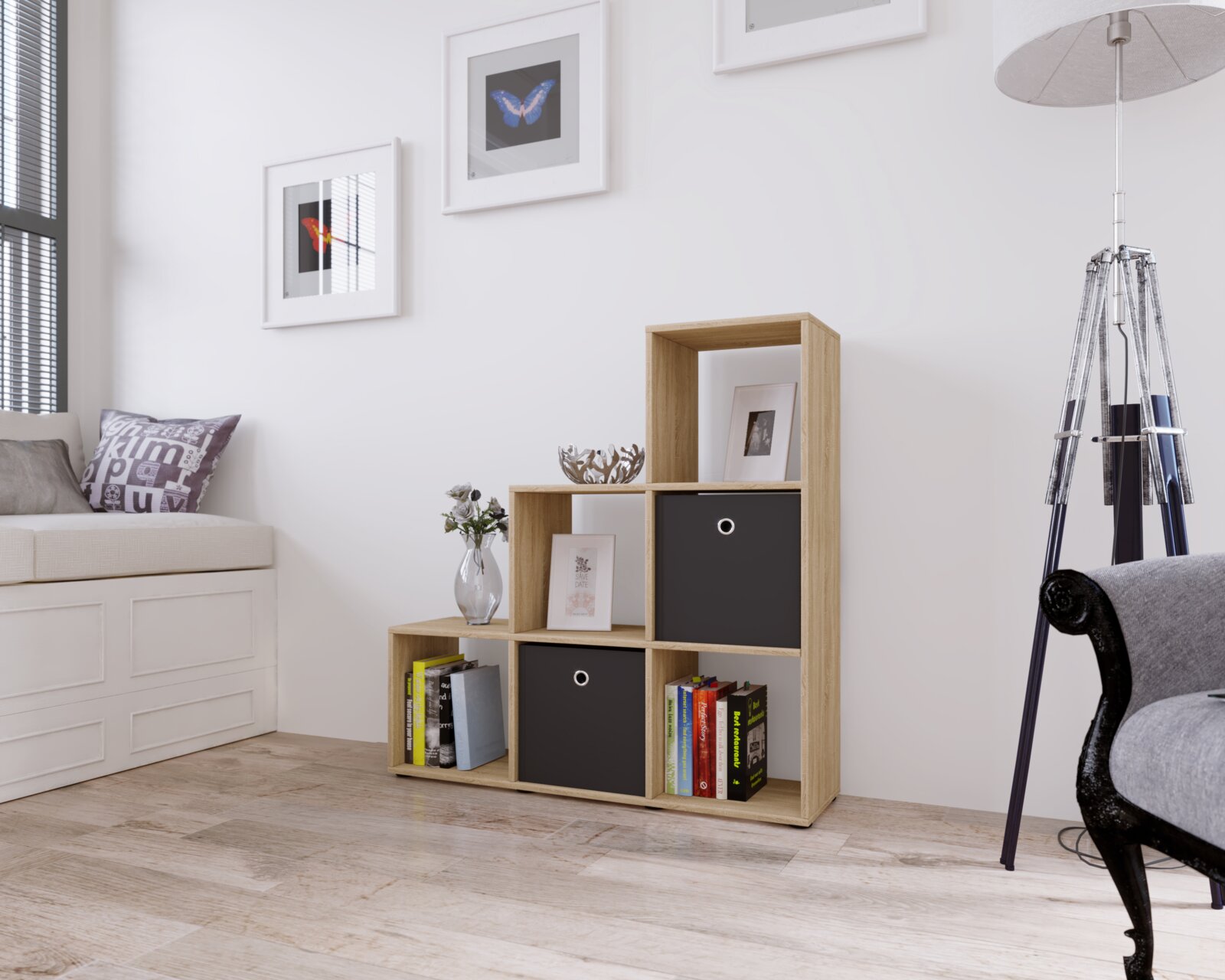 Modernes, stufenförmiges Regal in Eiche-Optik mit offenen Fächern, zwei schwarzen Stoffboxen und Büchern, freistehend an einer weißen Wand im Wohnzimmer; perspektivische Frontansicht leicht von links.