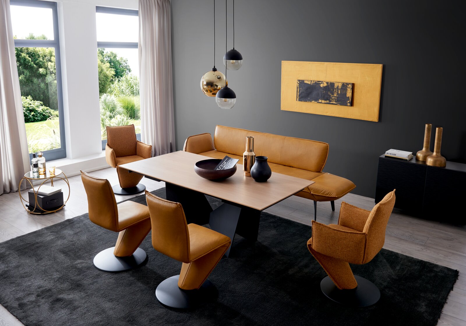 Moderne Esszimmer-Szene mit einem eleganten Holztisch, umgeben von stilvollen, drehbaren Stühlen und einer passenden Bank in warmen Brauntönen. Die Perspektive zeigt den Raum von schräg oben, mit Blick auf die harmonische Einrichtung und die großen Fenste