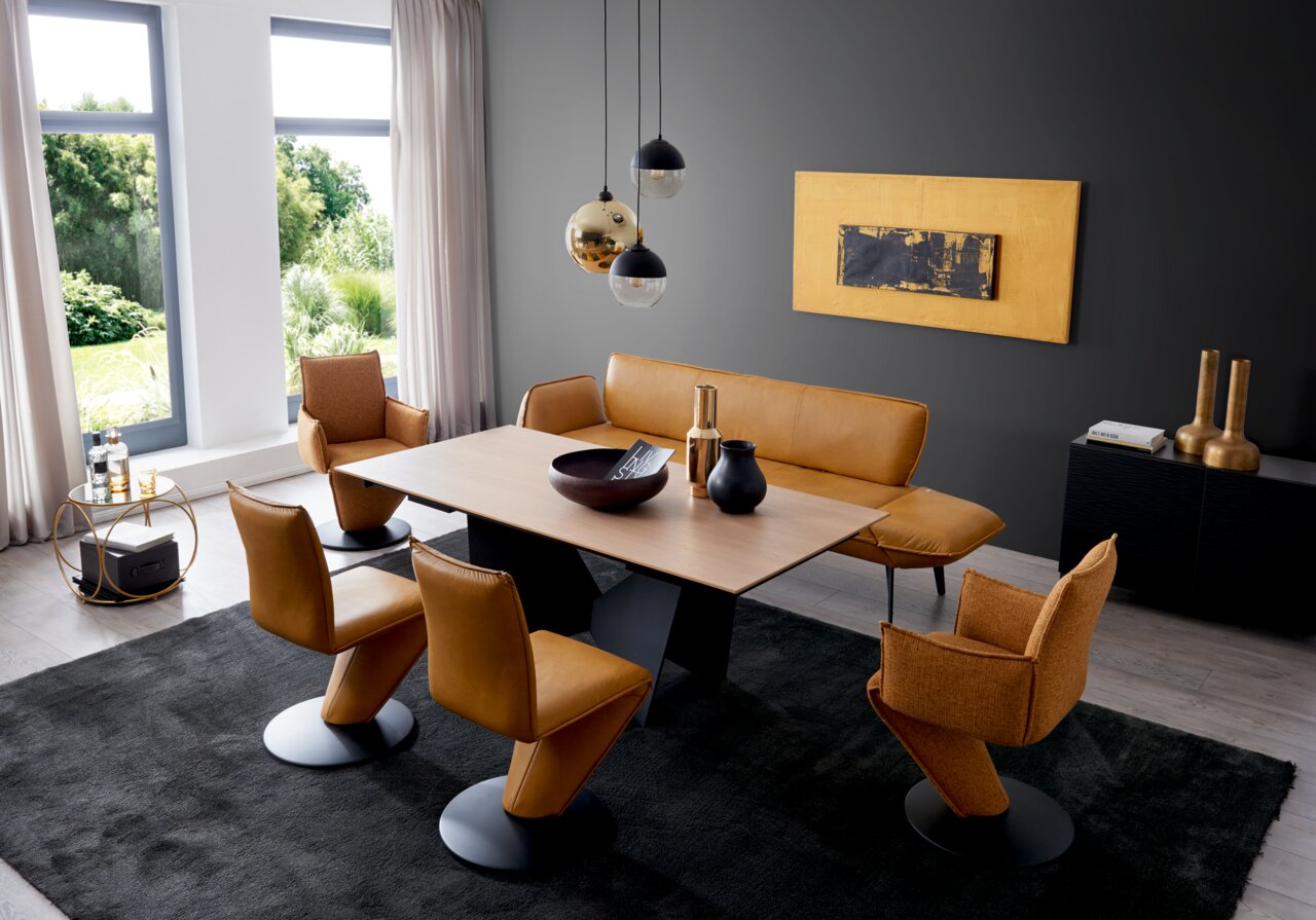 Een moderne eetkamer met een elegante houten tafel, omringd door stijlvolle draaistoelen en een bijpassende bank in warme bruintinten. Het perspectief toont de ruimte vanuit een schuine bovenhoek, met uitzicht op de harmonieuze inrichting en de grote rame