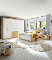 Moderne Schlafzimmermöbel mit einem sechstürigen Drehtürenschrank und einer Bettanlage in Holzoptik, seitliche Perspektive.