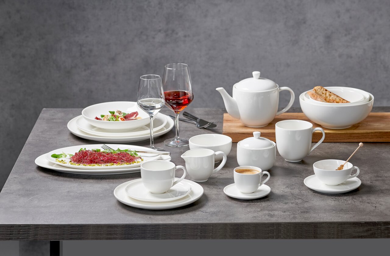 Ritzenhoff & Breker Milchkännchen SKAGEN Milchkännchen Skagen 180ml aus weißem Porzellan, seitliche Perspektive, auf einem gedeckten Tisch mit Geschirr und Gläsern.