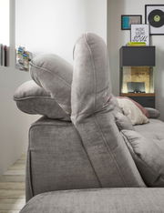 Seitenansicht einer grauen Rundecke mit verstellbaren Kopfstützen in einem modernen Wohnzimmer.
