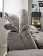 Seitenansicht einer grauen Rundecke mit verstellbaren Kopfstützen in einem modernen Wohnzimmer.