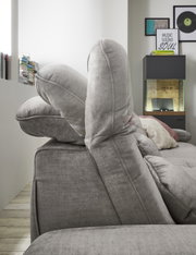 Seitenansicht einer grauen Rundecke mit verstellbaren Kopfstützen in einem modernen Wohnzimmer.