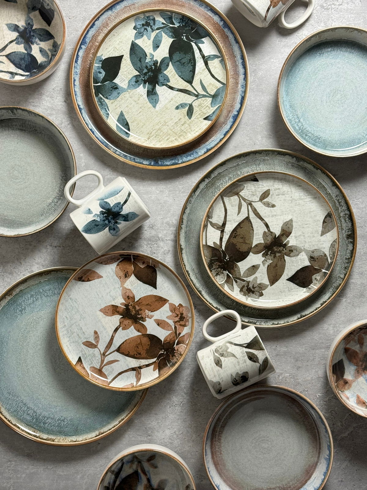 Vogelperspektive auf ein 30-teiliges Kombiservice mit floralem Design in Blau- und Brauntönen.