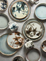 Vogelperspektive auf ein 30-teiliges Kombiservice mit floralem Design in Blau- und Brauntönen.