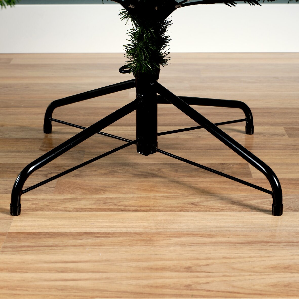 Metalen standaard van een kerstboom op een houten vloer, zijaanzicht