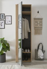 Garderobenschrank mit Spiegel, teilweise geöffnet, zeigt Innenraum mit aufgehängtem Mantel und Schuhen, aus seitlicher Perspektive fotografiert.